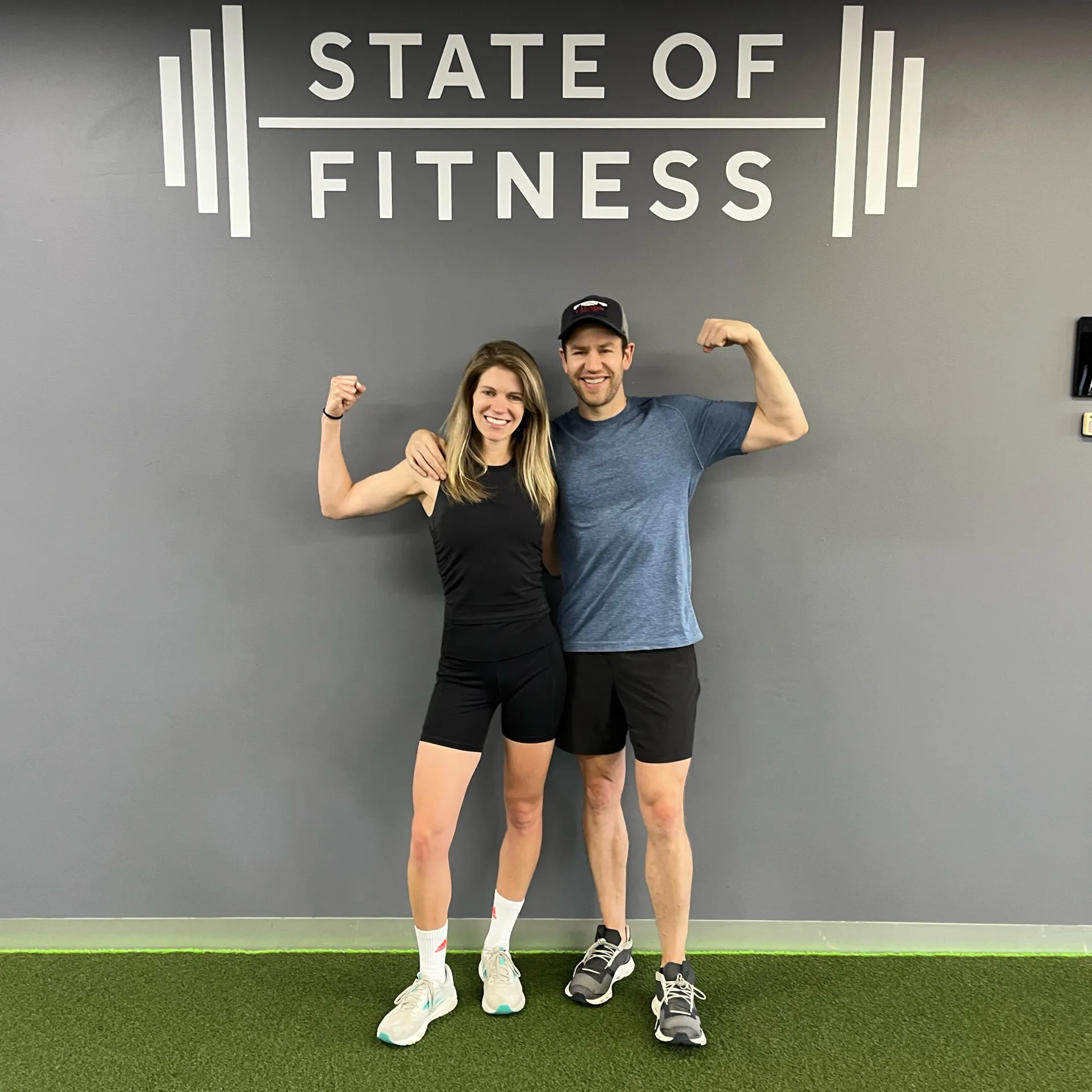 Liam, a State of Fitness coach, and Jess, a member, beneath the State of Fitness logo at the South Yarra studio