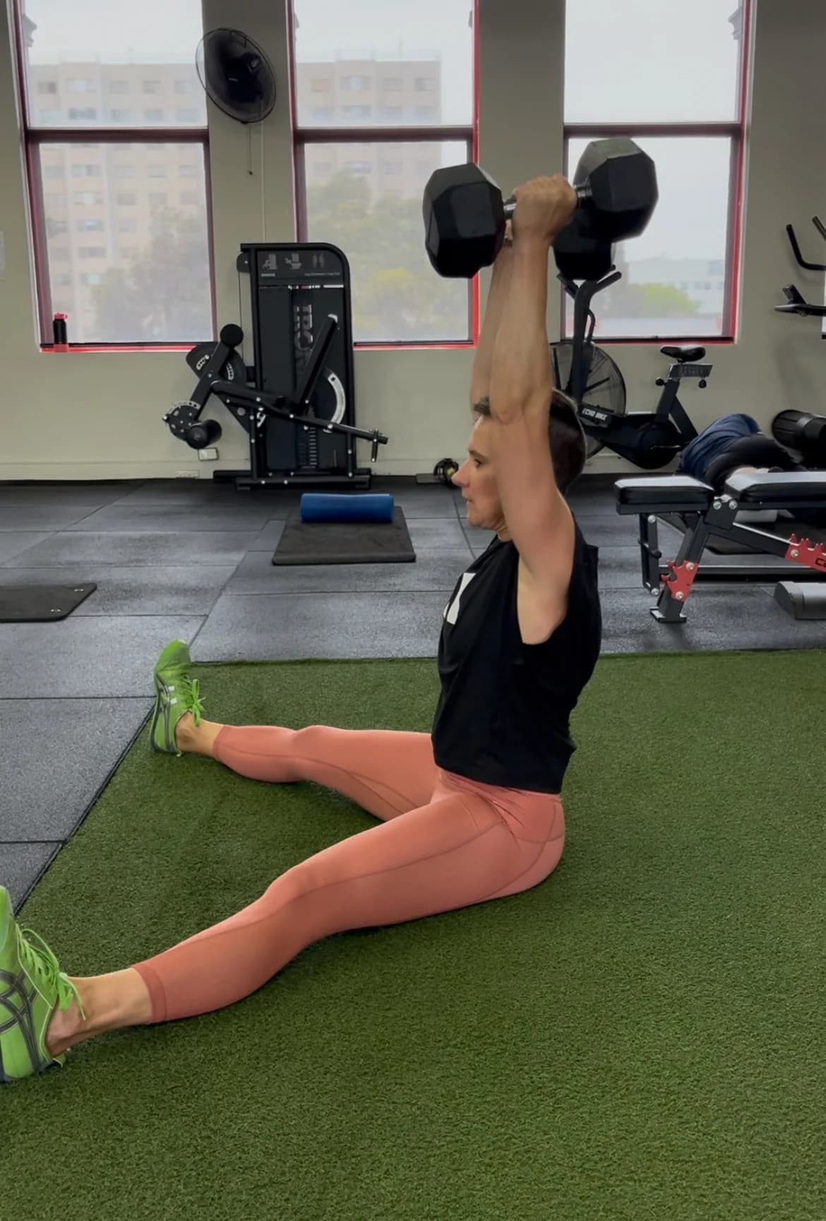 A State of Fitness member pressing dumbbells overhead during a session
