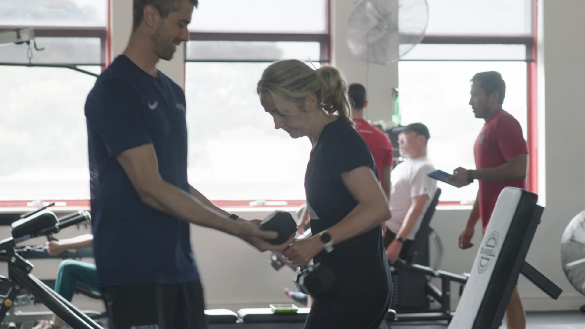 Scott handing a member a dumbbell while other members train their own programs at the State of Fitness studio in South Yarra