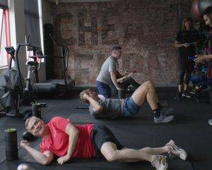 A group of people performing different exercises under the supervision of personal trainers, highlighting a dynamic and active fitness atmosphere.