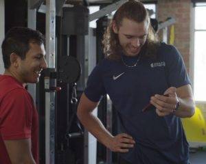 Two men in gym attire are looking at a cell phone together in a personal training studio.
