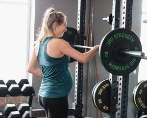 A pregnant woman exercises under the guidance of a personal coach, emphasising her active lifestyle during pregnancy.