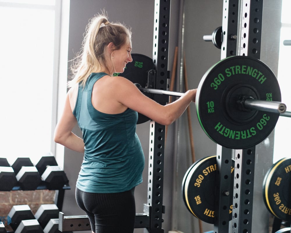 A pregnant woman exercises under the guidance of a personal coach, emphasising her active lifestyle during pregnancy.