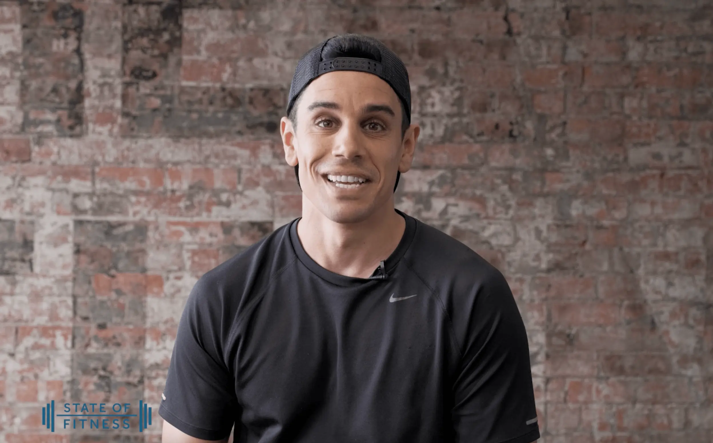 A man with a perfect smile wearing a black shirt and cap, exuding a friendly, cheerful and radiating positivity.
