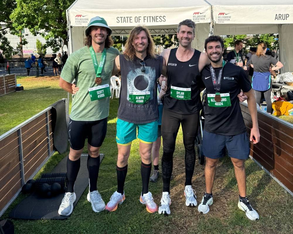 The State of Fitness studio team stands smiling in athletic gear at the Melbourne Marathon Festival.